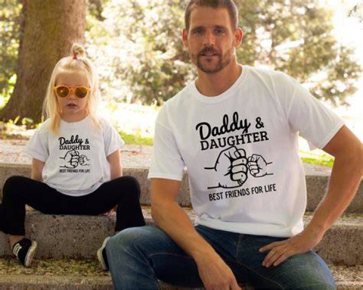 A daddy-daughter duo are pictured laughing together while watching TV and eating popcorn | Source: Shutterstock