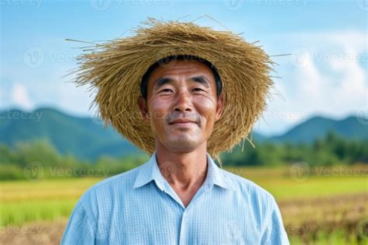 A farmer wearing rattan hat with his chicken on his lap. | Photo: Shutterstock