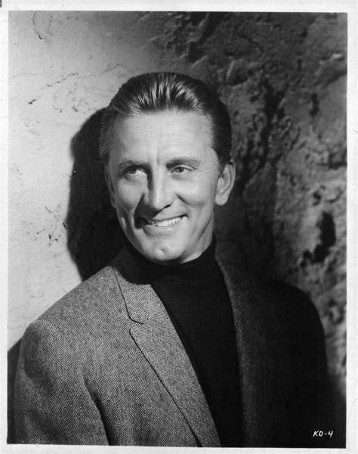 Actor Kirk Douglas receiving a kiss from his wife, Anne Buydens, between serving meals at the Los Angeles Mission and Anne Douglas Center's Thanksgiving Meal for the Homeless on November 23, 2005 in Los Angeles, California | Source: Getty Images