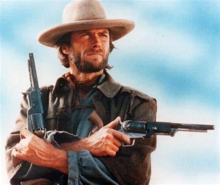 Clint Eastwood aiming a gun while Sandra Locke watches in a scene from the film 'Bronco Billy', 1980. | Photo: Getty Images