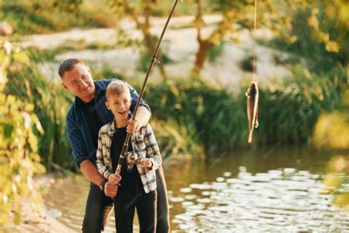 Father and son fishing together from a boat during sunset | Source: Shutterstock