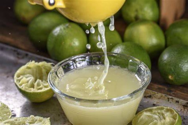 Freshly picked lime being squeezed for fresh lime juice on a vintage green glass juicer. | Photo: Getty Images