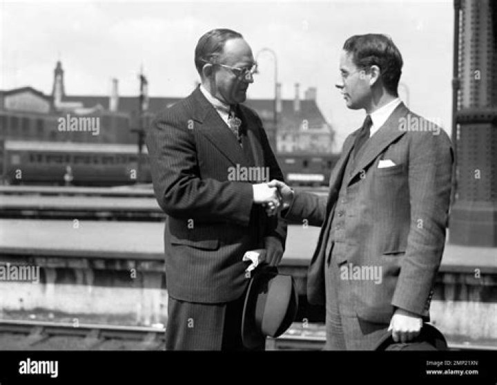 Oswald Pirow (left) shakes hands with Sir Oswald Mosley at London Airport as Lady Diana Mosley smiles behind (pictured left)