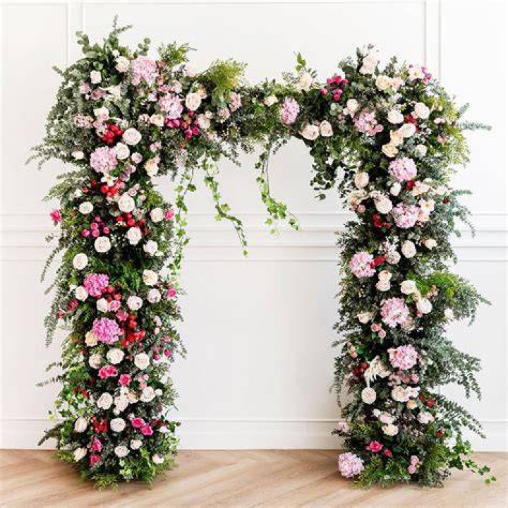 Pretty: Flower walls and arches around the church in the sleepy Hampshire village where the 'simple and beautiful' nuptials are taking place were being perfected as the drizzle set in