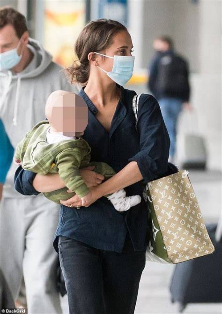 Sweet: Alicia Vikander, 32, was seen cradling a baby as she and husband Michael Fassbender, 44, travelled through Paris-Charles de Gaulle airport